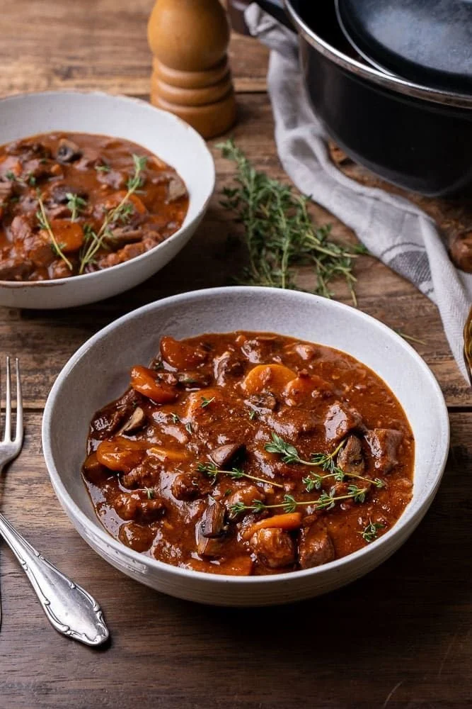 Un délicieux Boeuf Bourguignon garni de légumes et d'herbes fraîches