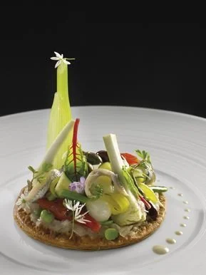 Tarte croustillante de salade niçoise avec légumes de saison et œuf moelleux.