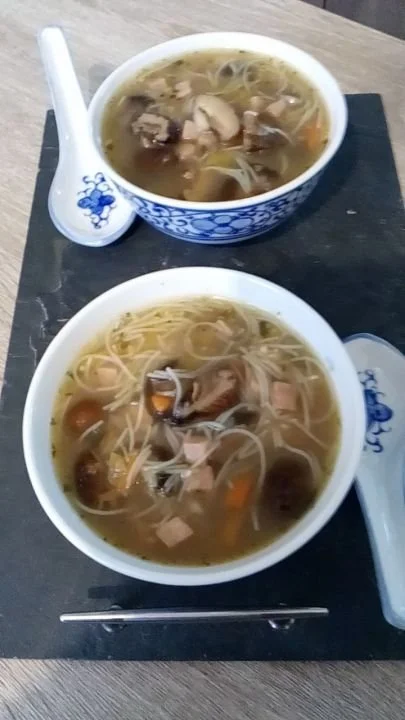 Soupe chinoise avec vermicelle de riz, champignons noir et poulet dans un bol.