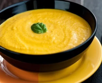 Bowl of creamy velouté de potiron garnished with herbs and seeds